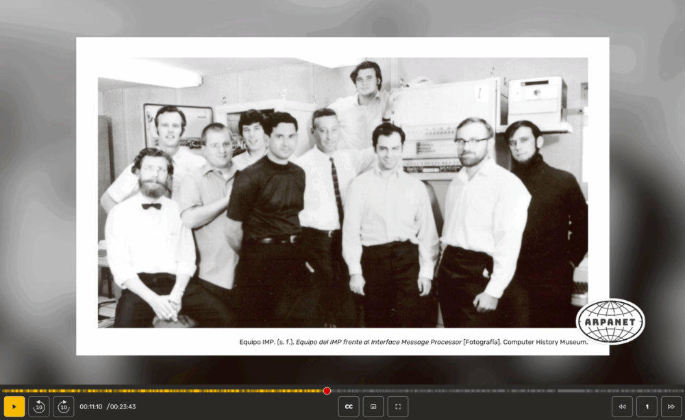 Fotografía en blanco y negro de un grupo de hombres posando frente al equipo Interface Message Processor (IMP), en un laboratorio.