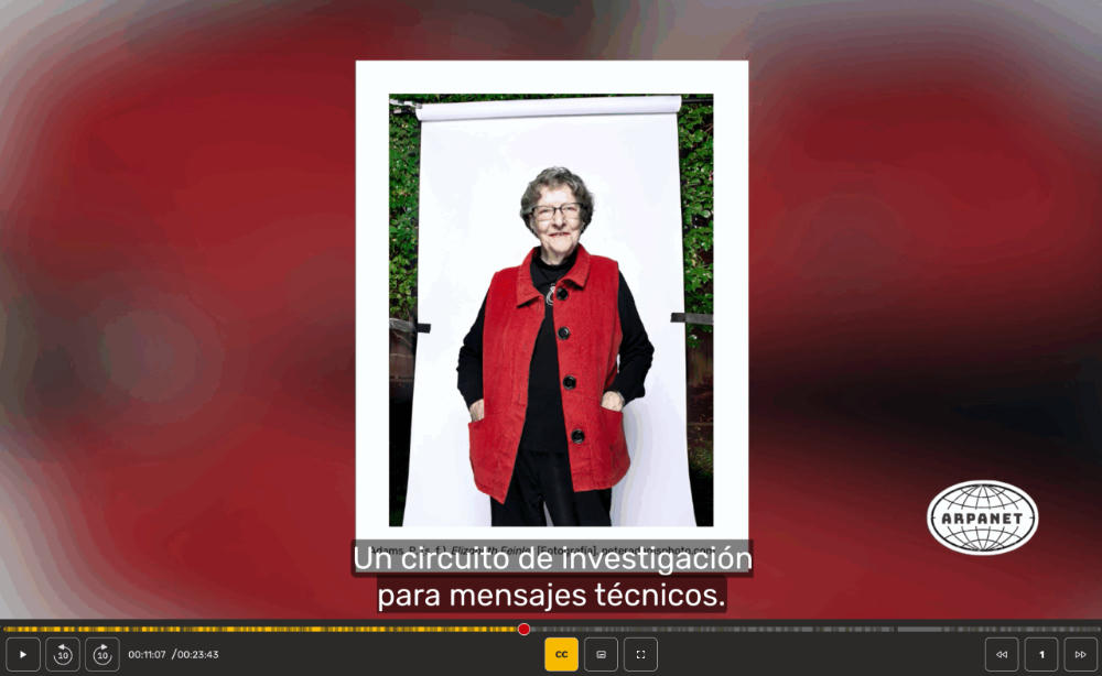 Retrato fotográfico de Elizabeth Feinler, con un chaleco rojo, posando de pie frente a un fondo blanco.